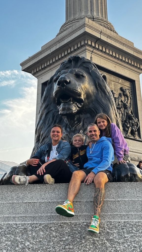 Photo de famille entre les pattes d'un lion, statues impressionnantes situées à Trafalgar Square à Londres